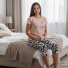 Devojka u roze pamučnoj majici i kapri pantalonama sa leopard dezenom sedi na krevetu – lifestyle prikaz ariljskog pamučnog programa Lotos.